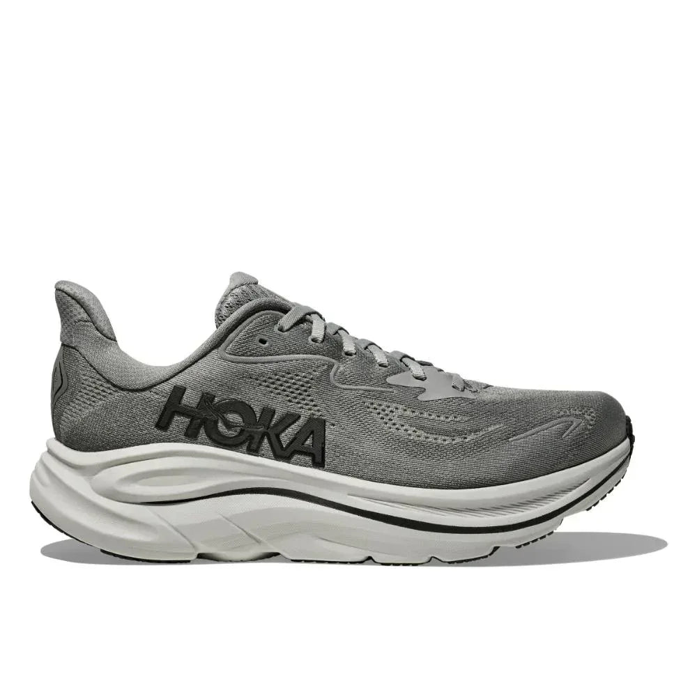 Hoka CLIFTON 10 1162030/GYST GALACTIC GREY הוא נעל ריצה אפורה עם סוליה לבנה ולוגו "HOKA" שחור ובולט בצד, המוצגת בפרופיל על רקע לבן נקי.