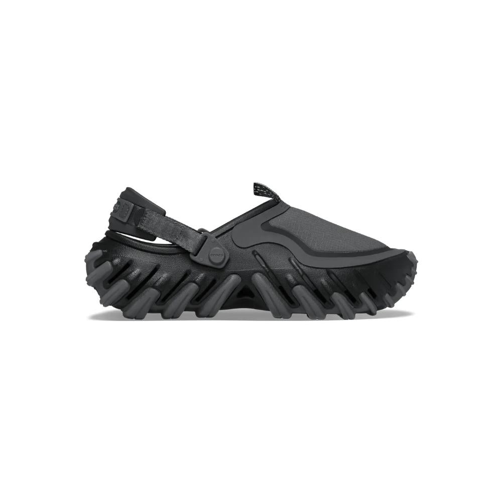 ה-Crocs Echo RO Ripstop Clog Black 211361-001 מבית Crocs הוא נעל בסגנון קלוג בצבע שחור עם סוליה מחוספסת ומגושמת ורצועת עקב מתכווננת, המוצגת במבט צדדי על רקע לבן.