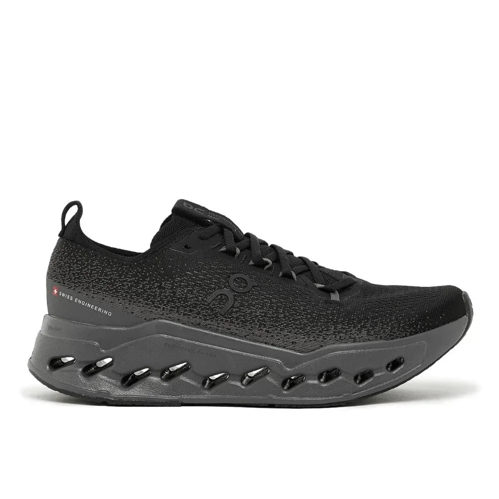 ה-On Cloudsurfer Max Black/Eclipse M 3MF30430106 מבית On Cloud הוא נעל ספורט שחורה עם גפה עליונה מרשת, עיצוב שרוכים וסוליה עבה בצבע אפור כהה עם חורי אוורור ובלימת זעזועים נראית לעין.