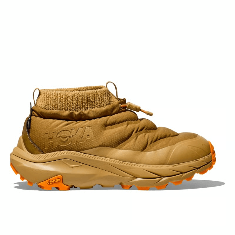 מבט צדדי של נעלי הוקה לגברים קאהה 2 פרוסט מוק Hoka 1155210/HYW KAHA 2 FROST MOC GTX HONEY/WHEAT slip-on עם חפת קרסול סרוג, סוליה עבה, סוליה כתומה ולוגו "Hoka" מובלט. נעליים אטומות למים.