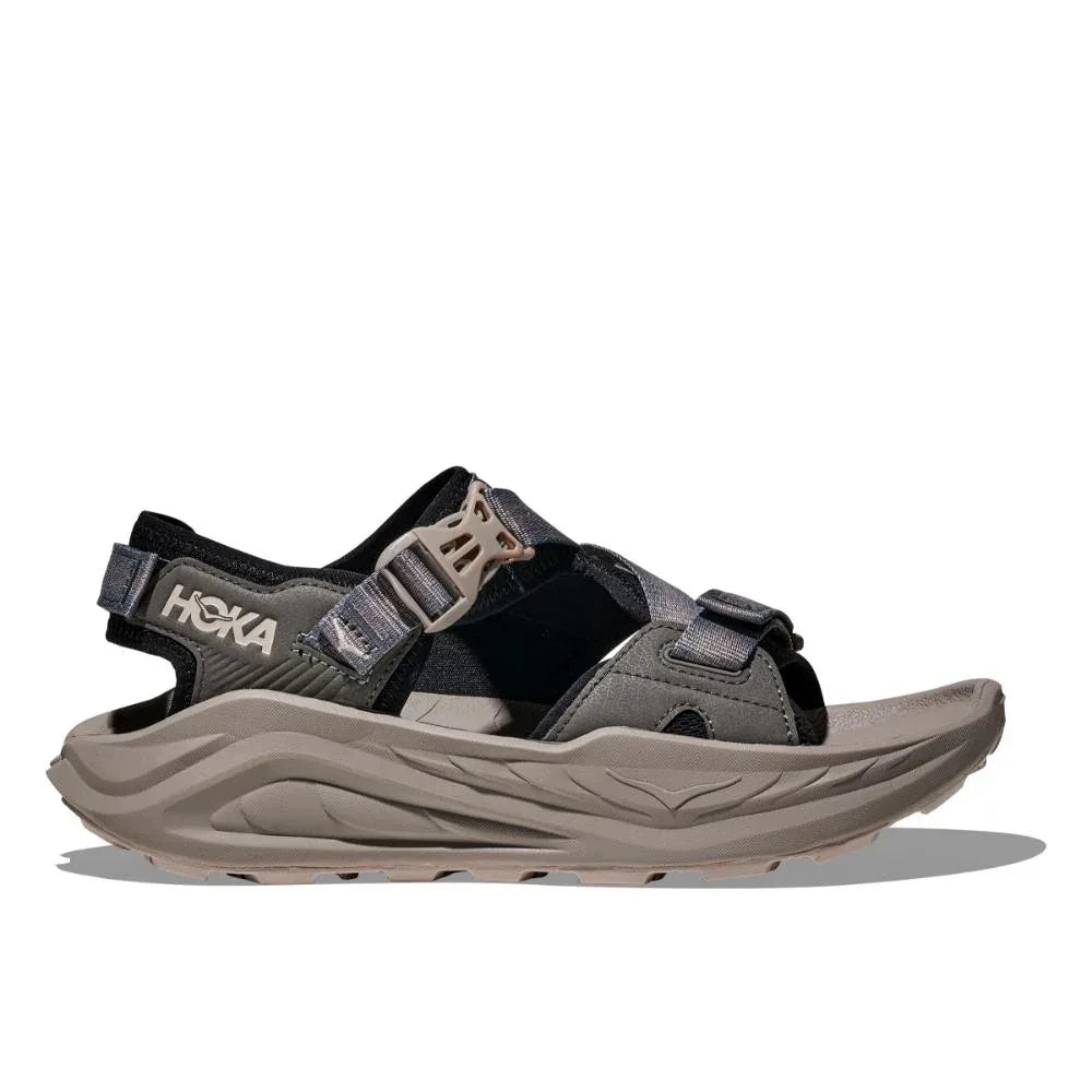 סנדל Hoka INFINI HIKE TC בודד בצבע שחור/בטון, עם רצועות מתכווננות וסוליה עבה ומותאמת למבנה כף הרגל, מוצג על רקע לבן.