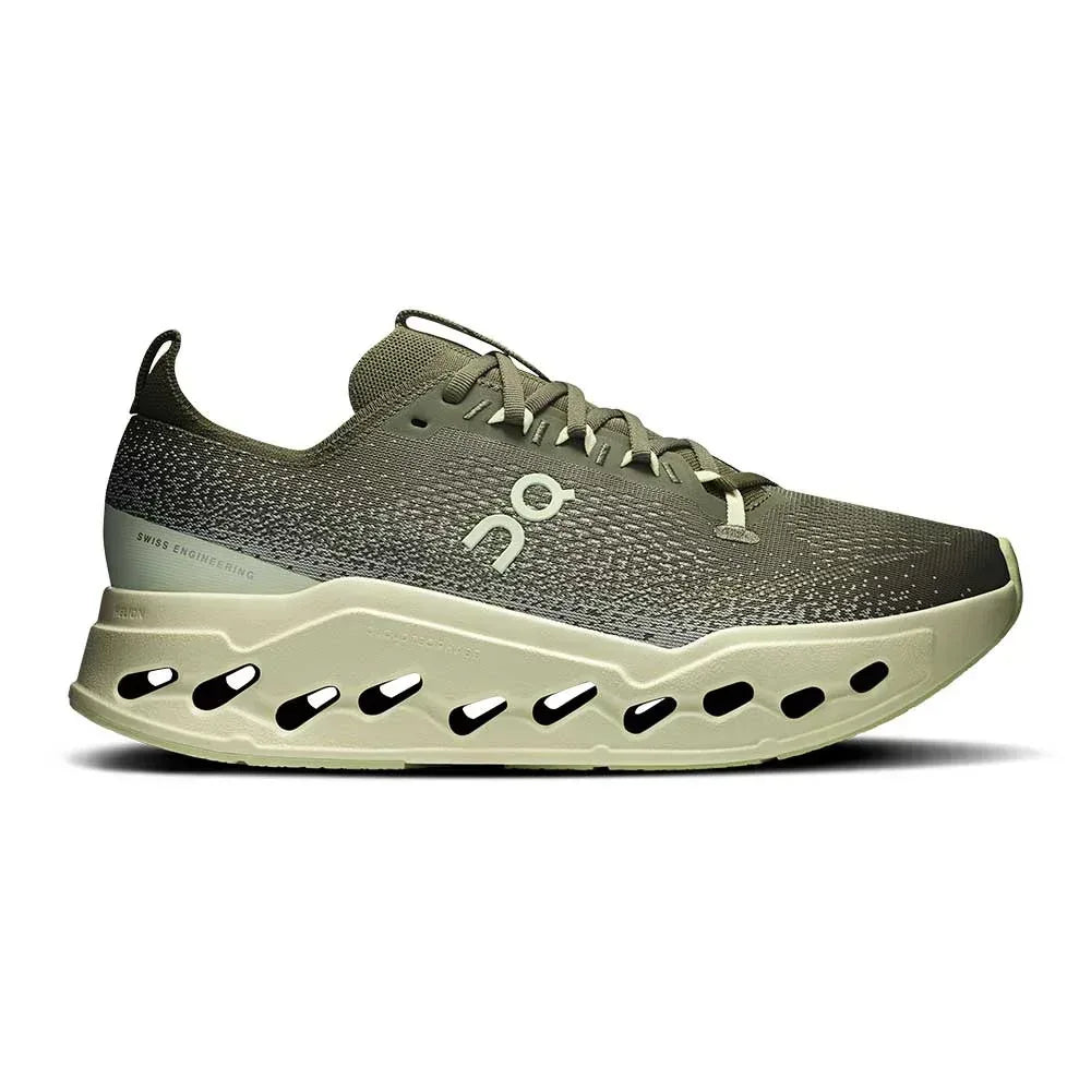 מבט צדדי על נעלי הספורט On Cloudsurfer Max 1 Olive/Seedling מבית On Cloud, המציגות את החלק העליון המרקם בצבע ירוק זית, הלוגו האופייני וסוליה עבה ומאווררת עם חורים לנידוף משופר.