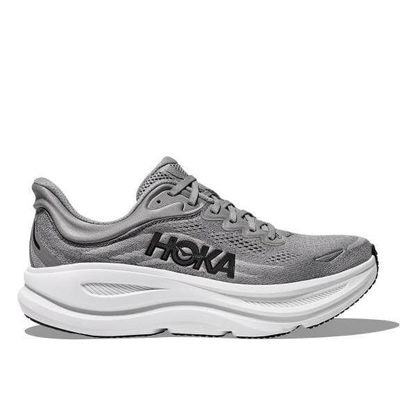 Hoka 1162013/GCTC BONDI 9 WIDE (2E) מתאפיין בעיצוב אתלטי אפור עם סוליה לבנה עבה ו"Hoka" בצבע שחור בצד.