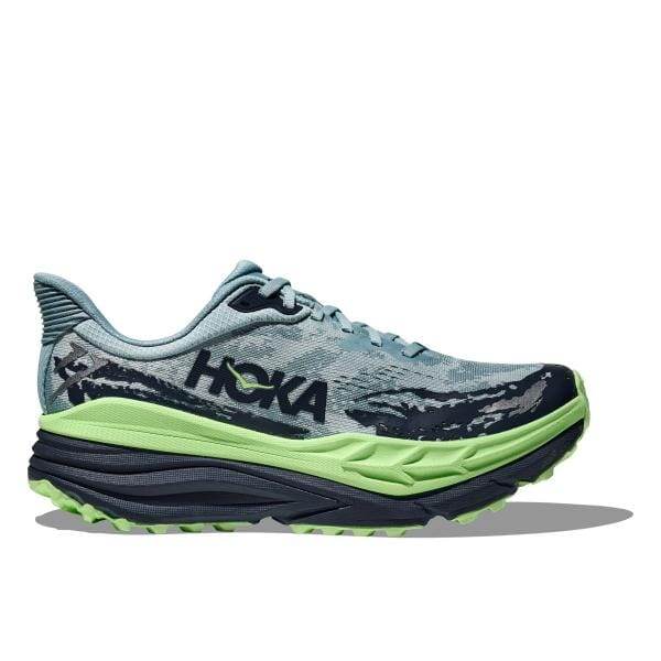 ה-Hoka STINSON 7 1141530/DYN ב-Druzy/Anchor היא נעל ספורט כחולה וירוקה עם סוליה עבה ומרופדת, עם המותג "Hoka" בצד.