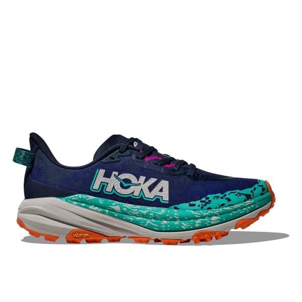 נעל הריצה Hoka 1147830/VYM SPEEDGOAT 6 WIDE, הכוללת שילוב של כחול וירוק עם הדגשים כתומים, מוצגת על רקע לבן. נעל זו מתהדרת בסוליה מחוספסת המושלמת לשטחים שונים.