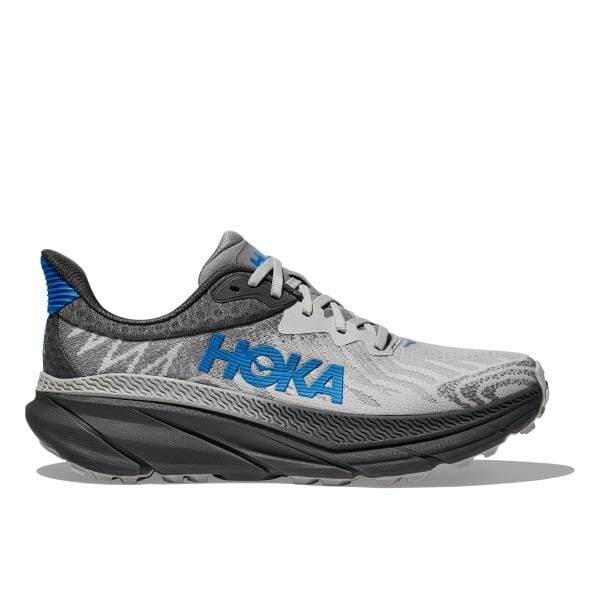 מבט מהצד של Hoka 1134499/OHK M Challenger Atr 7 Wide (2E) Outer Orbit, נעל ריצה אפורה עם הדגשות כחולות, הכוללת סוליה עבה עם מרקם ואת שם המותג Hoka בצד.