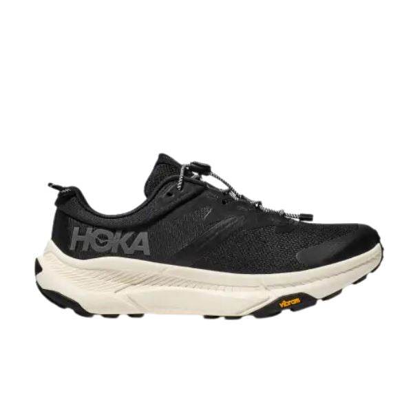 נעל הריצה Hoka 1164370/BKLB TRANSPORT WIDE של Hoka כוללת גפה שחורה עם סוליה לבנה ומיתוג גלוי בצד, משלימה סוליה חיצונית של Vibram לשיפור המשיכה.