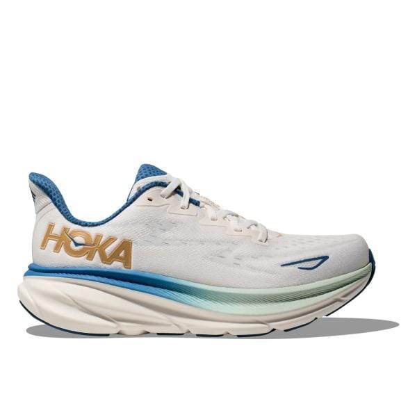 מבט מהצד של Hoka CLIFTON 9 WIDE (2E) 1132210/FTG, נעל אתלטית לבנה עם הדגשות כחולות, לוגו "HOKA" גדול בזהב וסוליית שכבות.