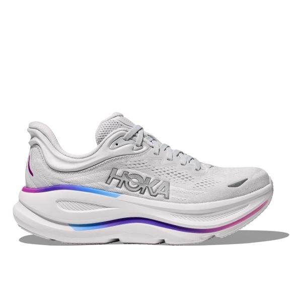 Hoka 1162014/CYWH BONDI 9 WIDE היא נעל ספורט לבנה עם מיתוג "HOKA", הכוללת סוליה עבה מרופדת והדגשים כחולים וורודים.