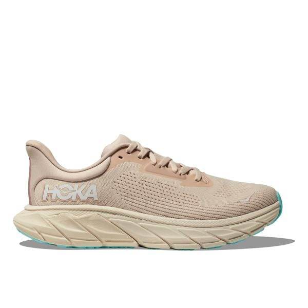 מבט מהצד של נעל הריצה Hoka ARAHI 7 Vanilla/Cream, מציגה את הסוליה המרופדת העבה, לוגו העקב והדגשי הטורקיז שלה בקצה.