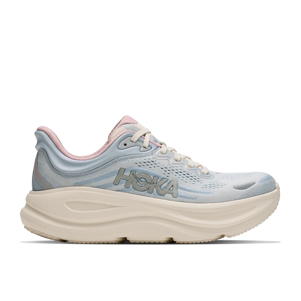 נעל ריצה Hoka Bondi 9 Wide לנשים בצבע Alabaster/Mineral — מבט צד חיצוני שמדגיש את לוגו HOKA ואת סוליית הקצף העבה בגובה 42 מ"מ בעקב.