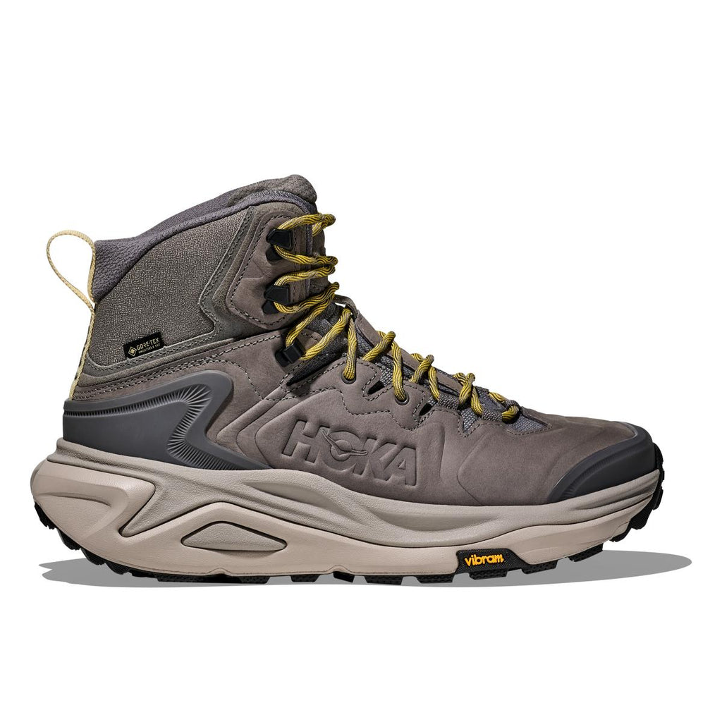 מגף הליכה Hoka Kaha 3 GTX לגברים בצבע Gravel/Cement — עור נובוק בגווני אפור ובז', שרוכים צהובים וסוליה שחורה.