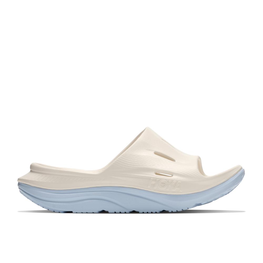 כפכפי התאוששות Hoka Ora Recovery Slide 3 בצבע Alabaster/Ambient – מבט צדדי עם גף בצבע שמנת, סוליה עבה תכלת וחריצי אוורור.