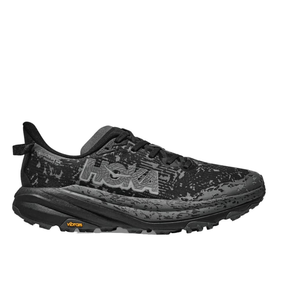 נעלי ריצת שטח Hoka SPEEDGOAT 6 GTX נגד מים בצבע שחור-אפור עם סוליה טקסטורה, לוגו HOKA על הצד ומיתוג Vibram בעקב, זמינות במידת רוחב רחב (2E) לגברים.
