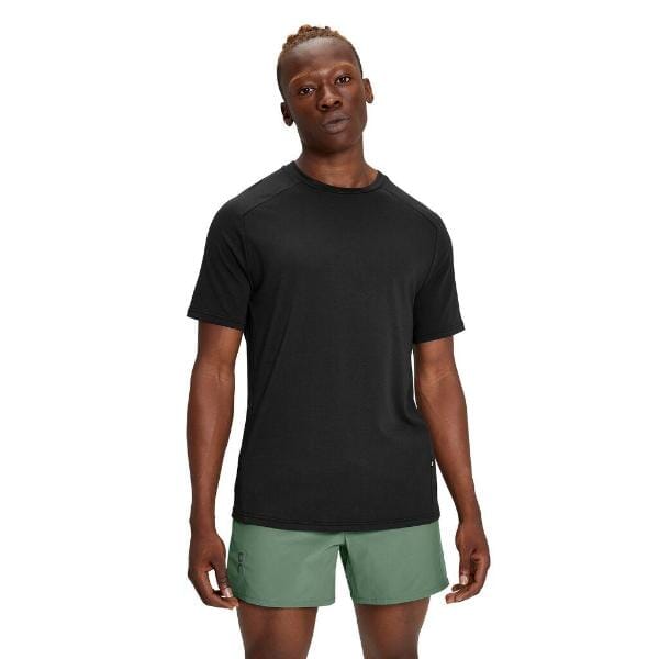 גבר לובש חולצת טריקו של On Cloud 1MD10060553 Focus-T ומכנסיים קצרים ירוקים עומד על רקע ניטרלי.