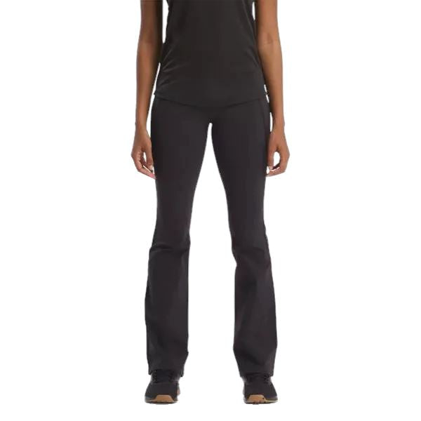 אישה לובשת ריבוק לוקס HR Mini Flare 100200804 עליונית ומכנסיים שחורים, עומדת על רקע שחור כשרק החלק האמצעי הקצוץ שלה נראה לעין.