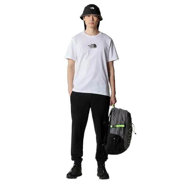 אדם לובש The North Face Fine Equipment Tee TEE TA87U3FN4, מכנסיים שחורים, נעלי ספורט שחורות וכובע דלי שחור, מחזיק תיק גב The North Face.