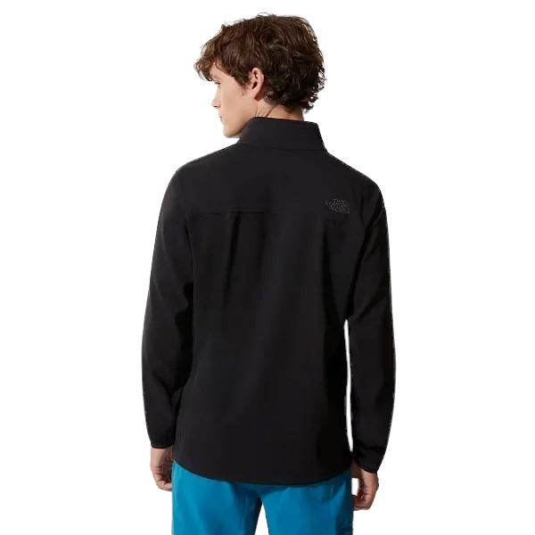 אדם עם שיער קצר ומתולתל לובש The North Face Nimble JacketT92TYGJK3 ומכנסיים כחולים מוצג מאחור, עומד על רקע לבן.